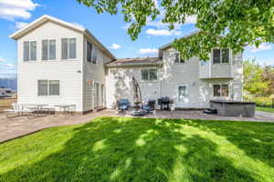 Back of house featuring a patio area, a hot tub, and a lawn