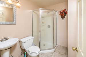 Bathroom with tile floors, an enclosed shower, and toilet