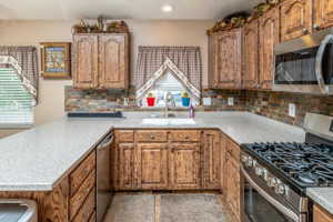 Kitchen featuring sink, light stone counters, backsplash, and appliances with stainless steel finishes