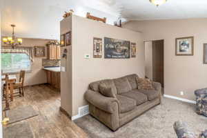 Living room featuring a notable chandelier, hardwood / wood-style floors, and lofted ceiling