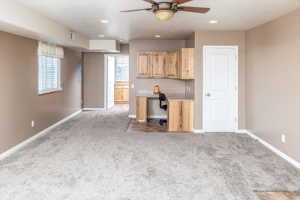 Kitchen with light brown cabinets, carpet, and ceiling fan