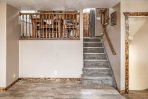 Stairs featuring hardwood / wood-style floors and a textured ceiling