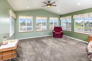Living area featuring carpet floors, ceiling fan, and vaulted ceiling