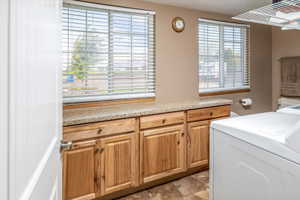 Washroom with washer / dryer, cabinets, a wealth of natural light, and light tile floors