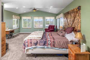 Bedroom featuring lofted ceiling, ceiling fan, carpet floors, and multiple windows