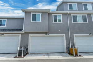 View of property featuring a garage and central AC unit