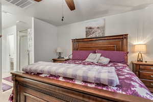 Carpeted bedroom featuring ensuite bath and ceiling fan