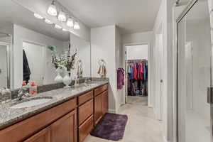 Bathroom featuring dual vanity, a shower with door, and tile floors