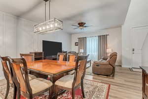 Dining space featuring ceiling fan with notable chandelier and light hardwood / wood-style flooring