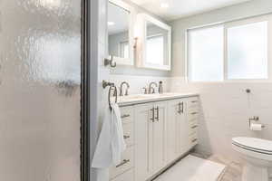 Master Bathroom featuring a large vanity, dual sinks, and tile walls