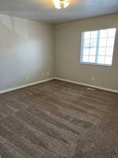 Spare room featuring a textured ceiling and dark carpet