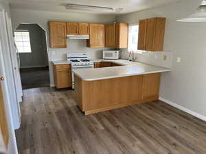 Kitchen with kitchen peninsula, hardwood / wood-style flooring, sink, white appliances, and a textured ceiling