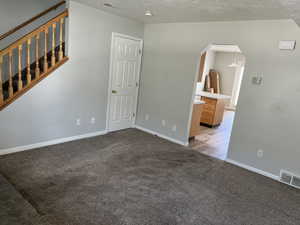 Carpeted spare room featuring vaulted ceiling and a textured ceiling