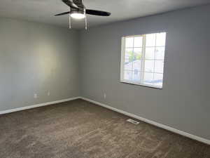 Carpeted empty room with ceiling fan and a textured ceiling