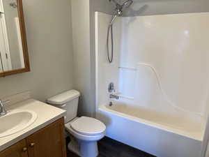 Full bathroom with shower / bath combination, hardwood / wood-style floors, toilet, and vanity