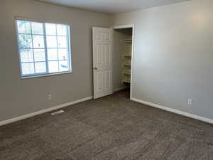 Unfurnished bedroom featuring dark colored carpet, a closet, and a walk in closet