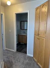 Hall with sink, a textured ceiling, and dark carpet