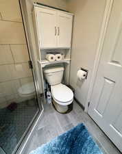 Bathroom with hardwood / wood-style flooring, toilet, and walk in shower