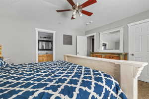 Carpeted bedroom featuring connected bathroom and ceiling fan