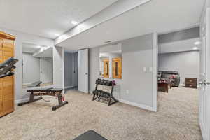 Exercise area featuring light carpet and a textured ceiling