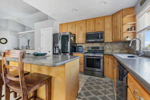 Kitchen featuring backsplash, a kitchen bar, appliances with stainless steel finishes, sink, and light tile floors