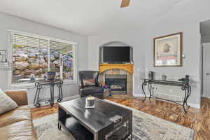 Living room featuring hardwood / wood-style flooring, a tiled fireplace, and ceiling fan