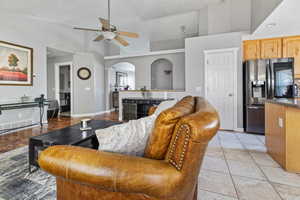 Living room featuring high vaulted ceiling, ceiling fan, and light tile flooring