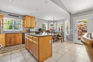 Kitchen with a center island, a chandelier, tasteful backsplash, and light tile flooring