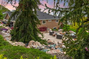 Back house at dusk featuring outdoor lounge area and a patio