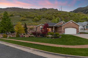 View of front of property featuring a yard, a garage, and a mountain view