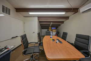 Office space with carpet, beam ceiling, and a wall mounted air conditioner