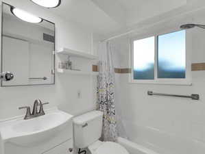 Full bathroom with toilet, vanity, and shower / bath combo