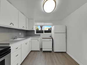 Kitchen featuring light hardwood / wood-style flooring, tasteful backsplash, white fridge, sink, and white cabinets