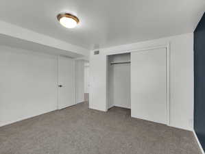 Unfurnished bedroom featuring dark carpet and a closet