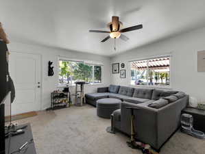 Carpeted living room featuring ceiling fan