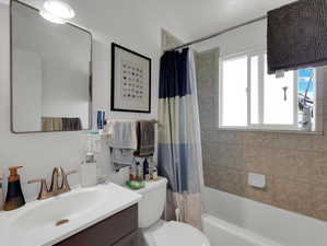 Full bathroom featuring shower / bathtub combination with curtain, toilet, and vanity with extensive cabinet space