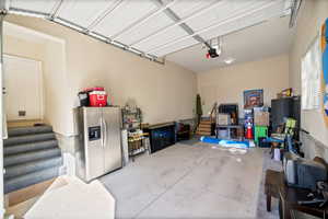 Garage featuring stainless steel fridge and a garage door opener