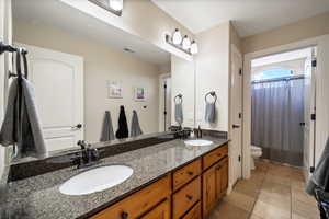 Bathroom with tile floors, double vanity, and toilet