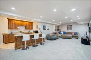 Basement kitchen with a kitchen breakfast bar, custom cabinets and light stone counters.