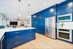 Kitchen featuring appliances with stainless steel finishes, ceiling fan, blue cabinets, and light hardwood / wood-style flooring