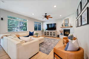 Great room featuring light hardwood / wood-style floors, a fireplace, and ceiling fan