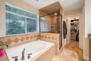 Master Bathroom featuring tile floors, jetted tub,  plus a walk in shower