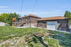 Rear view of house with a deck, a garage, a yard, and central AC unit