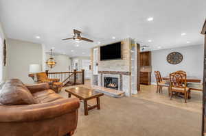 Living room with light tile floors, ceiling fan, and a fireplace