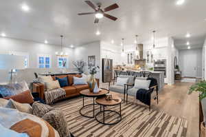 Living room with light hardwood / wood-style flooring and ceiling fan with notable chandelier