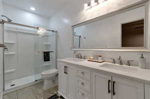 Bathroom featuring dual vanity, tile flooring, an enclosed shower, and toilet