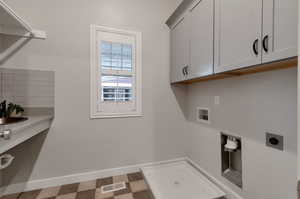 Clothes washing area with tile floors, washer hookup, electric dryer hookup, and cabinets