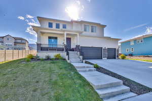 View of front of home featuring a front yard, a porch, and a garage