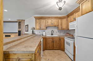 Kitchen with white appliances, sink, tasteful backsplash, and light tile floors