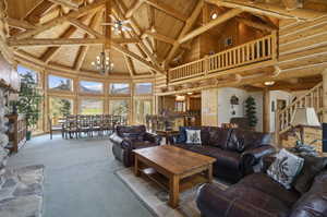 Carpeted living room featuring high vaulted ceiling, wooden ceiling, a chandelier, and beam ceiling